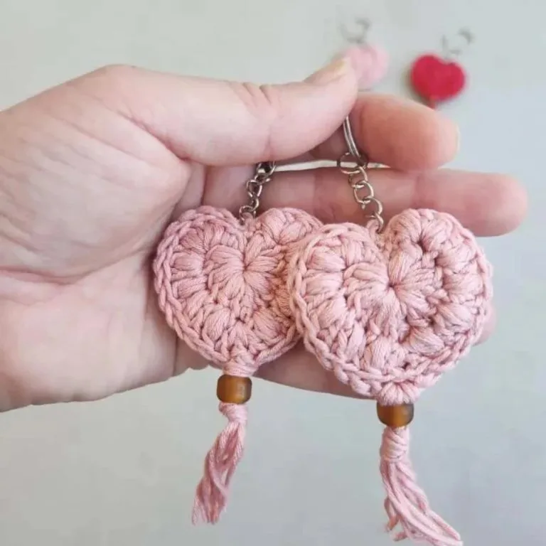 A hand holding a crochet heart keychain adorned with wooden beads, showcasing a beautiful handmade gift.