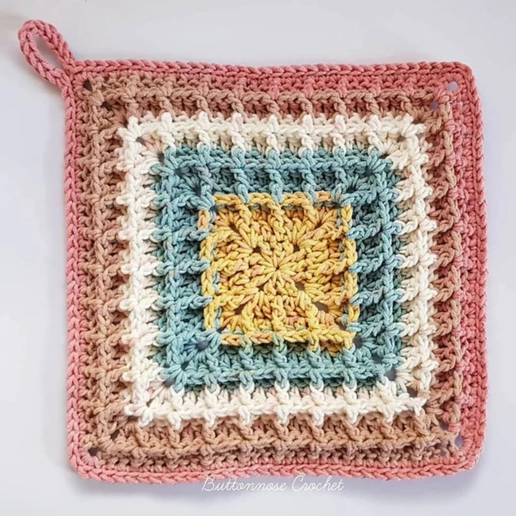 A crochet granny square piece with different colors and a hanger loop.