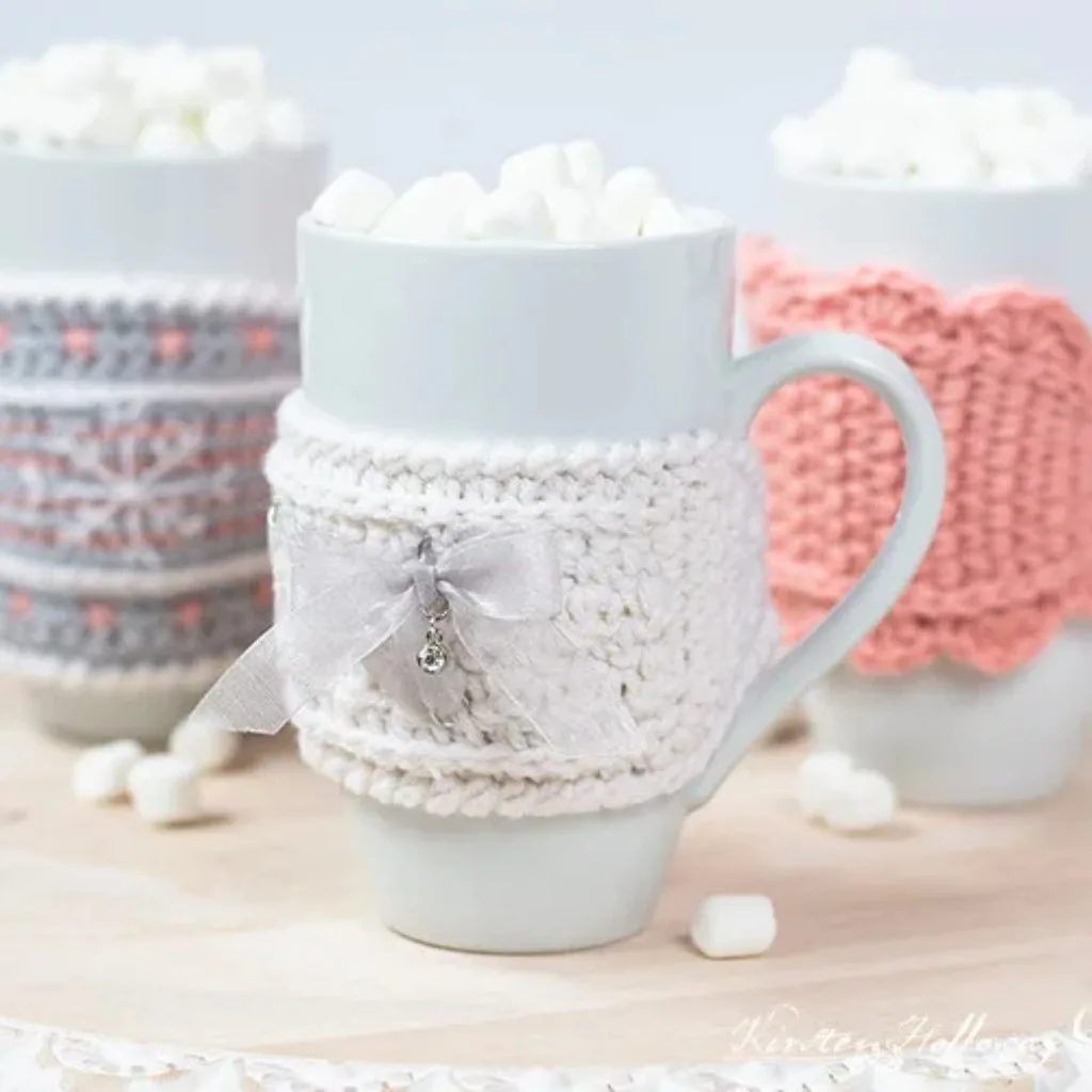 Three cups in crochet sleeves filled with marshmallows.