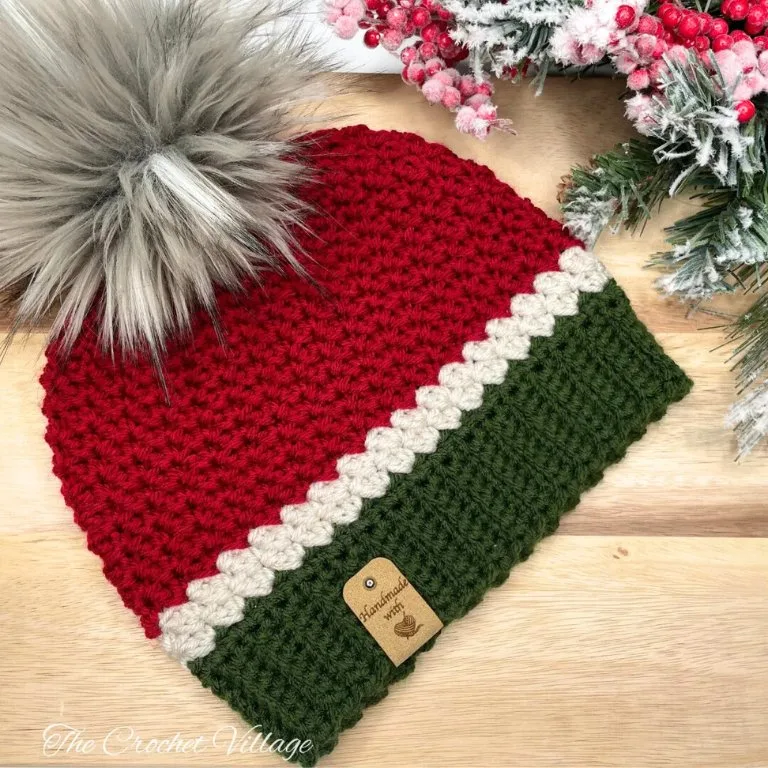 A crochet beanie in Christmas colors on a wooden surface