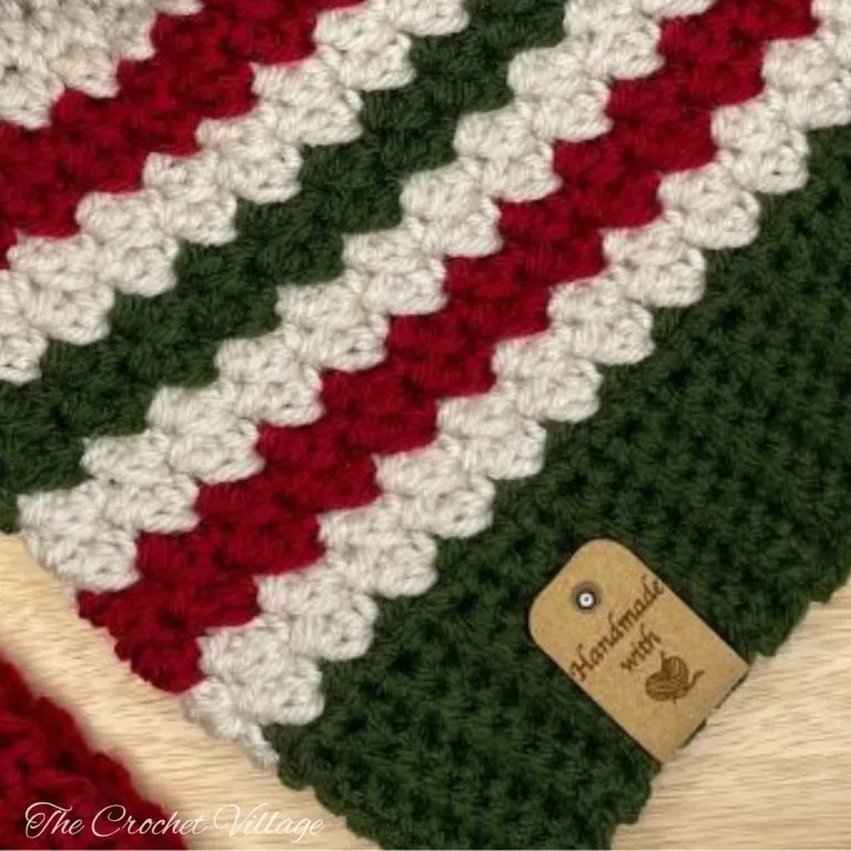 A close-up of a crochet piece showing beautiful textured stitches in classic Christmas colors—deep red, forest green, and creamy white.