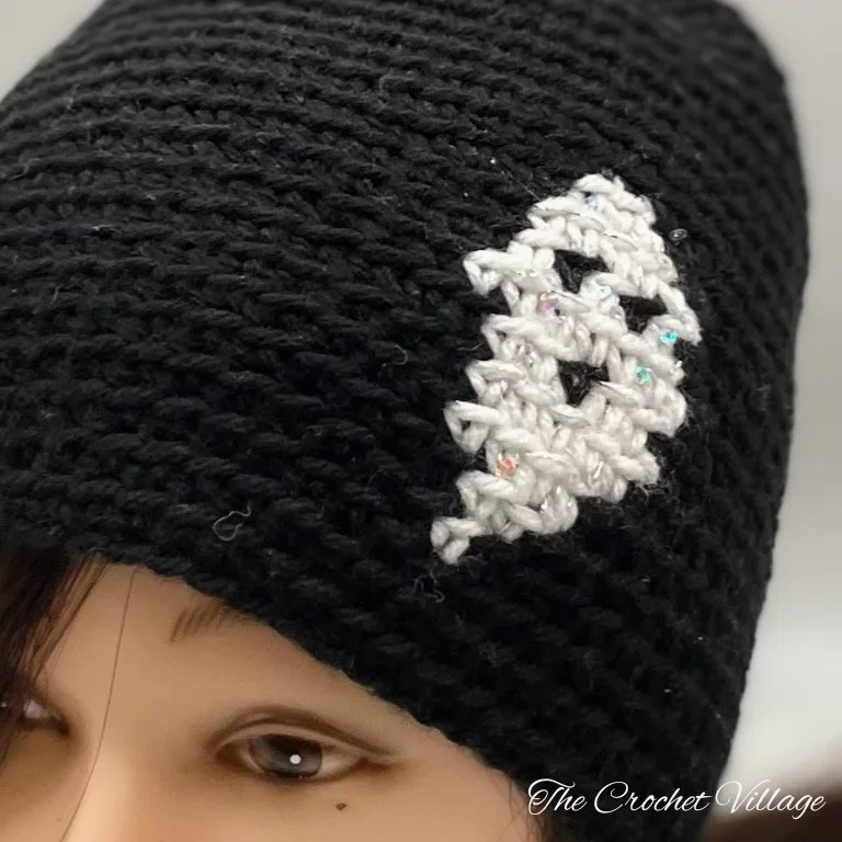 A close-up of a crochet hat featuring a ghost print design, perfect for Halloween.