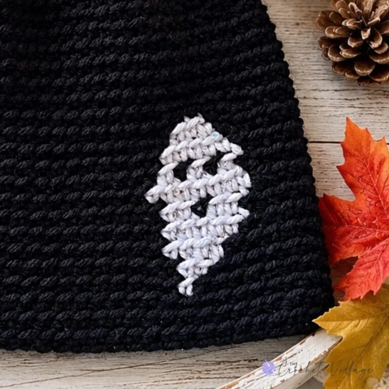 A close-up of a crochet hat featuring a ghost print design, perfect for Halloween.