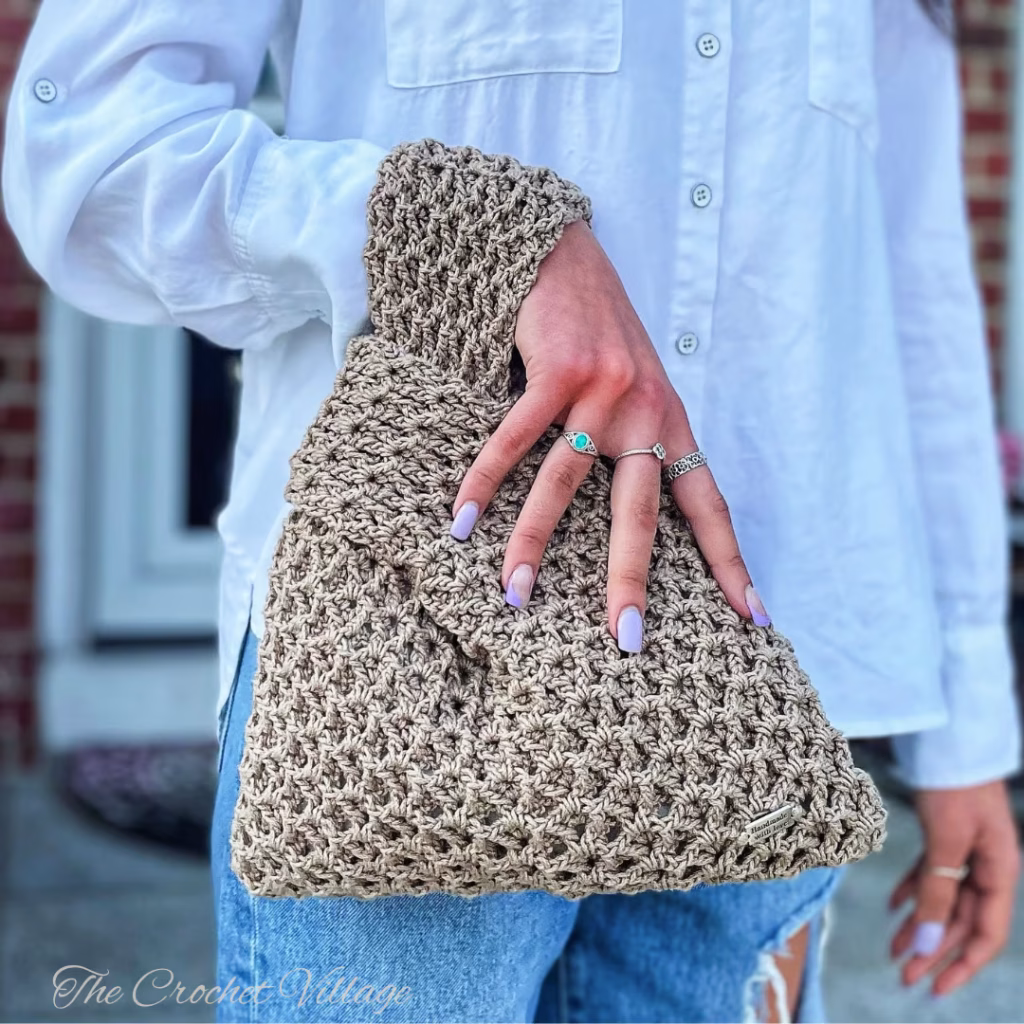 A girl's hand holding a crochet Japanese knot bag with a stylish, textured design.