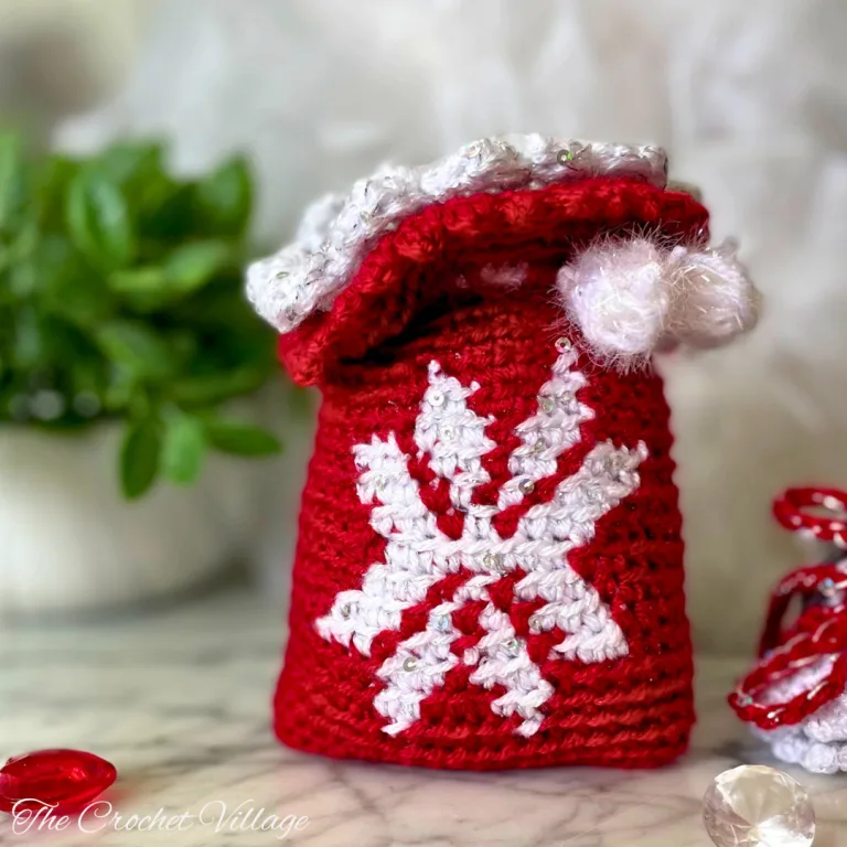 A crochet gift bag featuring a snowflake design—an adorable handmade drawstring pouch perfect for Christmas gifting!