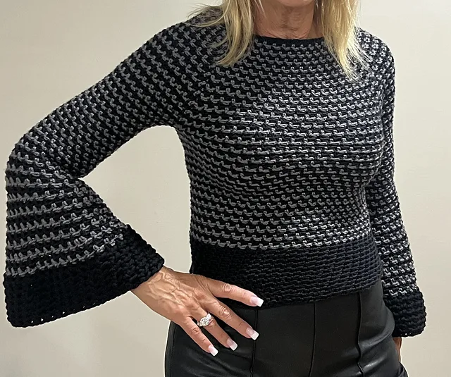A woman wearing a simple crochet top down raglan-style sweater.