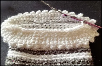 Close-up of a crochet hook with a small crochet gift bag in progress.