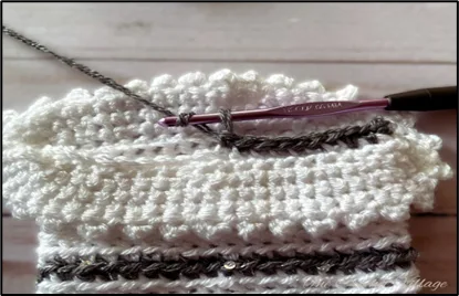 Close-up of a crochet hook with a small, unfinished crochet gift bag in progress.