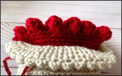 The top of a small crochet bag featuring 2 layers and scalope edging.