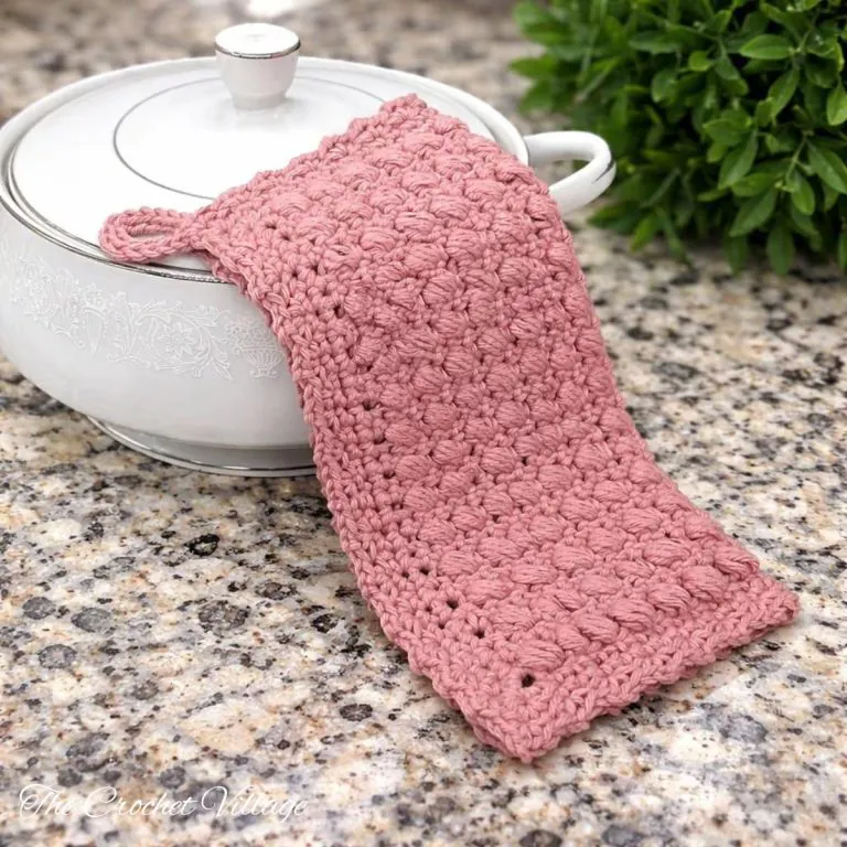 Lucia's textured crochet potholder draped over a ceramic pot on a kitchen counte