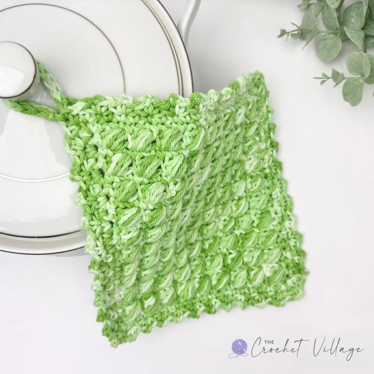 Handmade crochet potholder and basket of hot pads on a kitchen counter – free crochet pattern