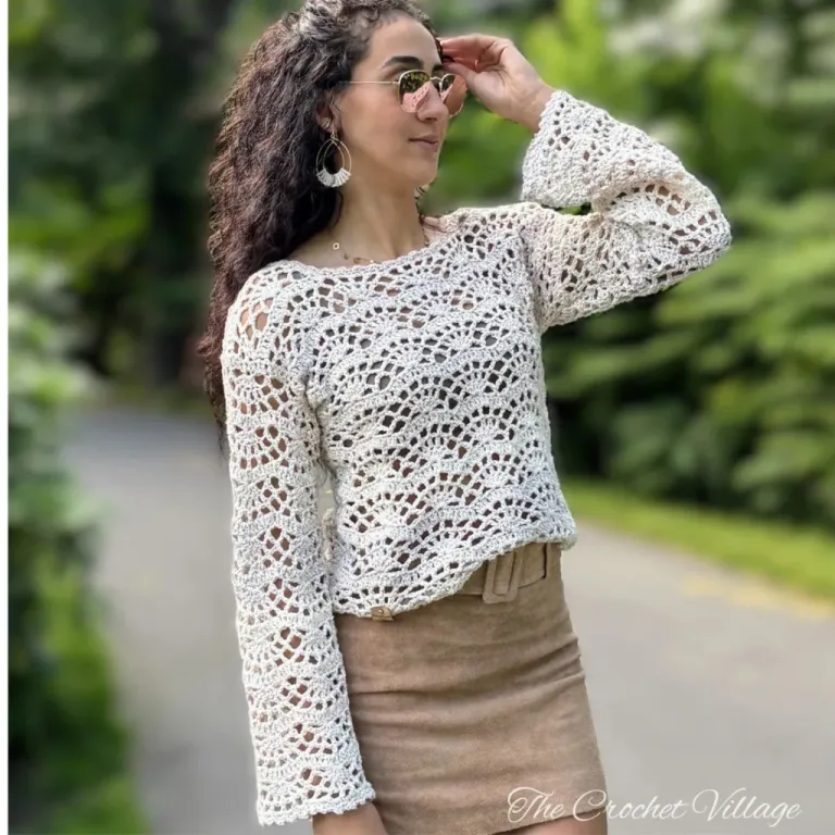 Woman wearing lightweight lacy crochet Charlotte sweater in cream over white tank top