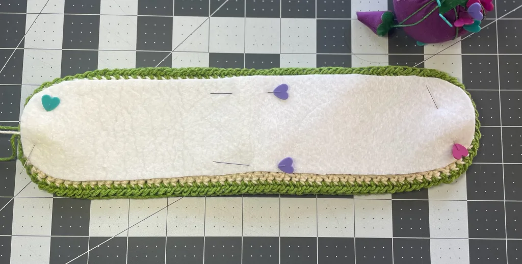 A fabric interfacing pinned to a crochet piece to reinforce it.