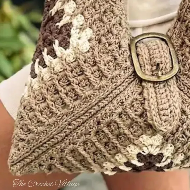 A close up of a crochet granny square bag featuring a metal buckle closure.