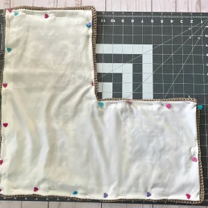Close-up image showing a piece of fabric pinned to the inside of a crochet shoulder bag to demonstrate how to line the bag.