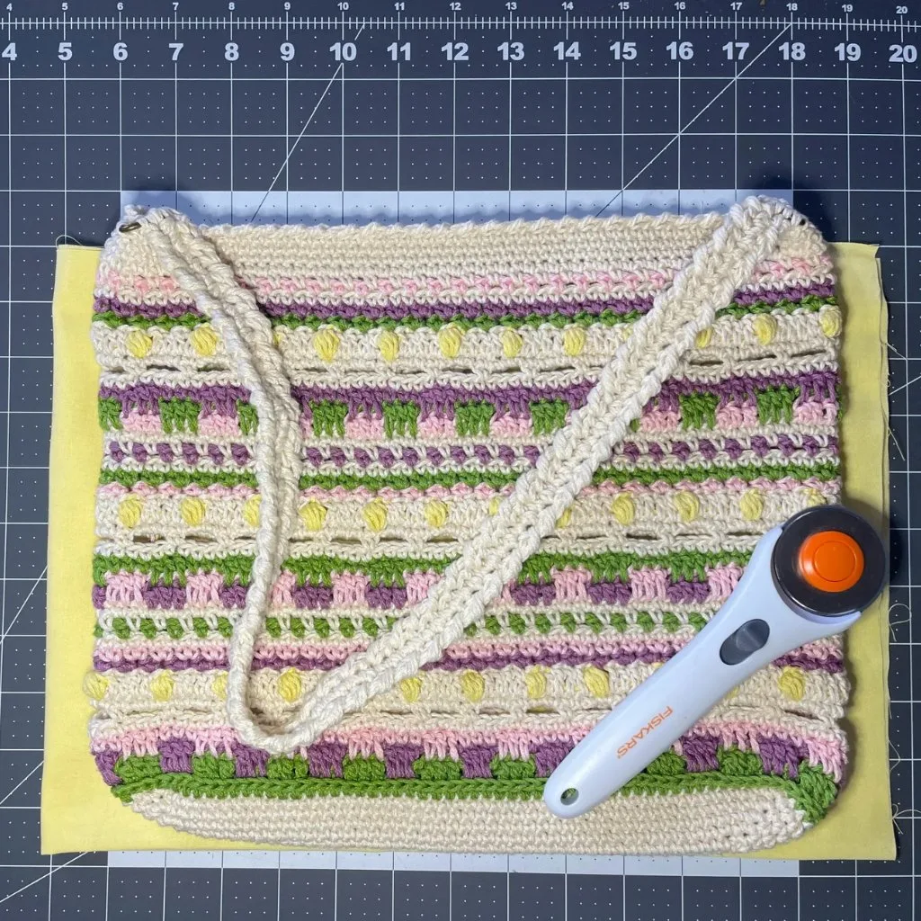 A crochet bag placed on top of lining fabric, ready for sewing.