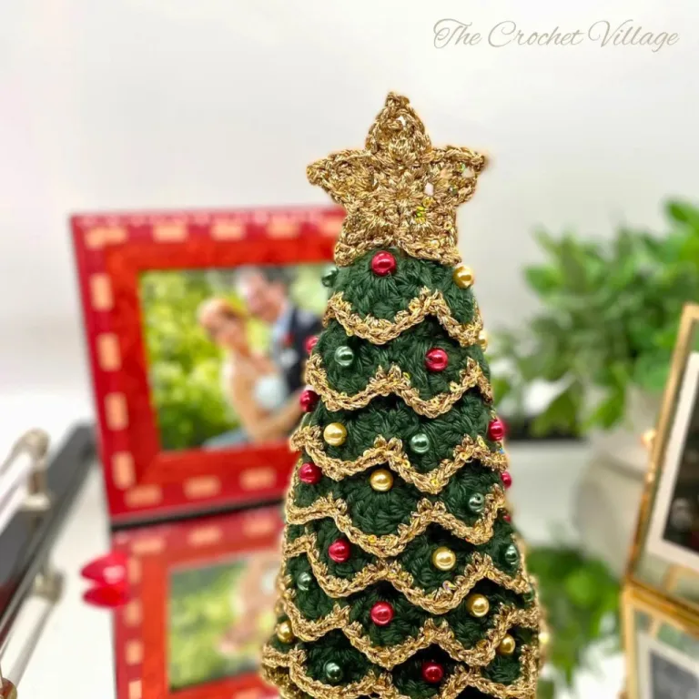 A small and realistic 3D crochet Christmas tree with a gold edging, star on top, and golden beads for a sparkling touch.