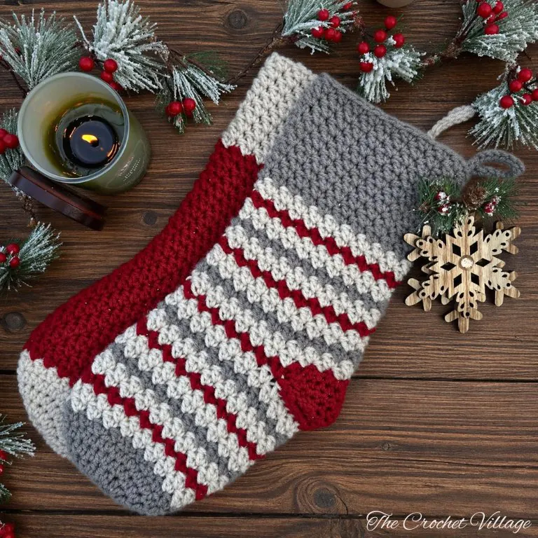Flat lay arrangement of multiple classic crochet Christmas stockings in various colors with holiday décor on wooden background