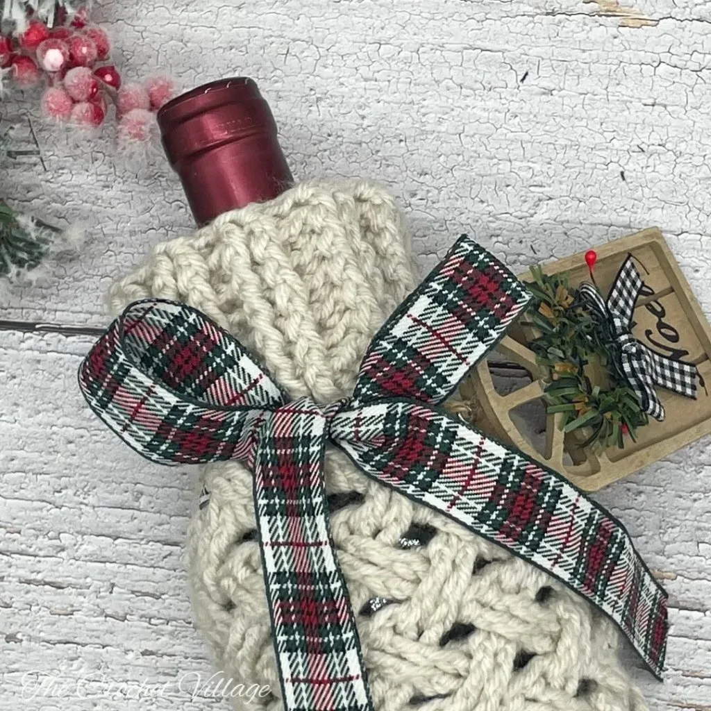 Close-up of the top of a wine bottle inside a crochet bag, showcasing the textured stitch and decorative details.