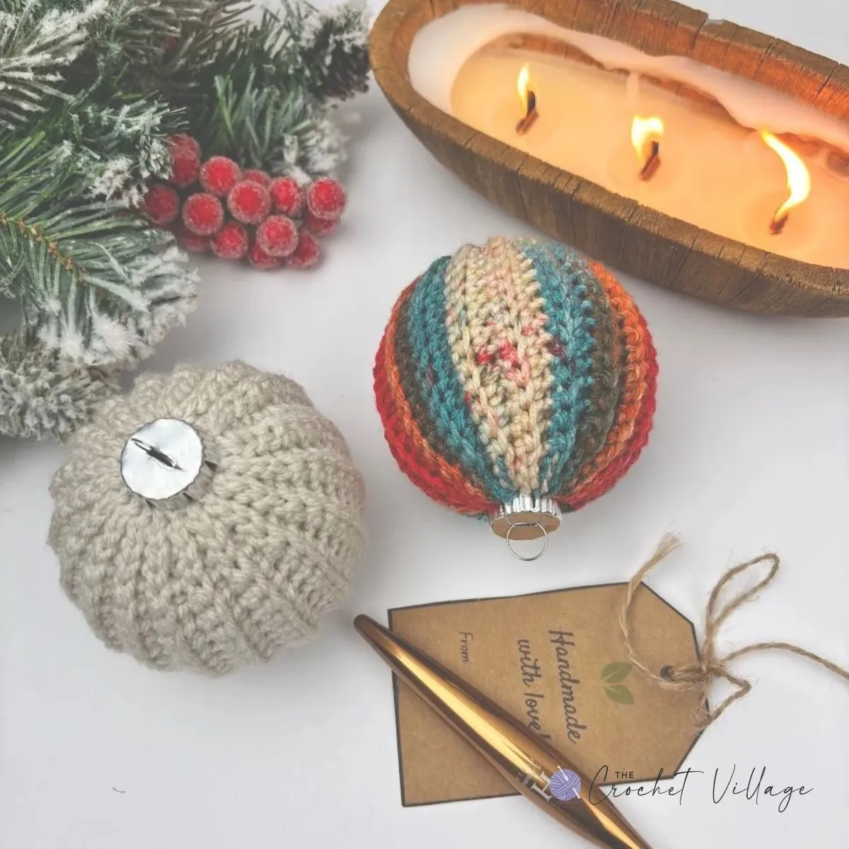 Two crochet Christmas bauble covers one in variegated yarn and one in a solicd color yarn beside a gold crochet hook and a handmade gift tag