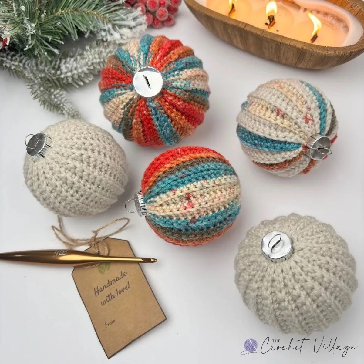 Five crochet Christmas bauble covers in cream and variegated red, teal, and orange yarn, with silver buttons and a gold crochet hook