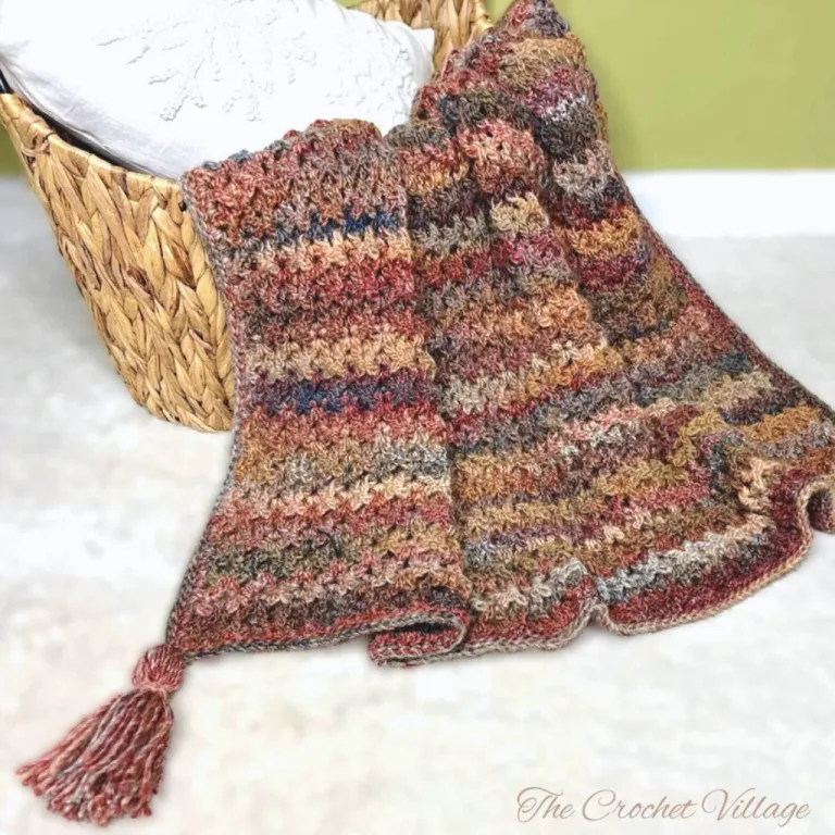 A gorgeous textured crochet throw blanket neatly placed in a basket on a white carpet.