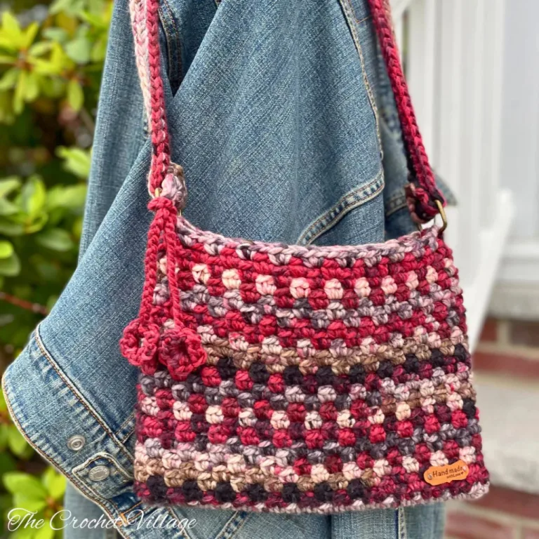 A colorful chunky crochet crossbody bag displayed on a denim jacket draped over a stair railing.