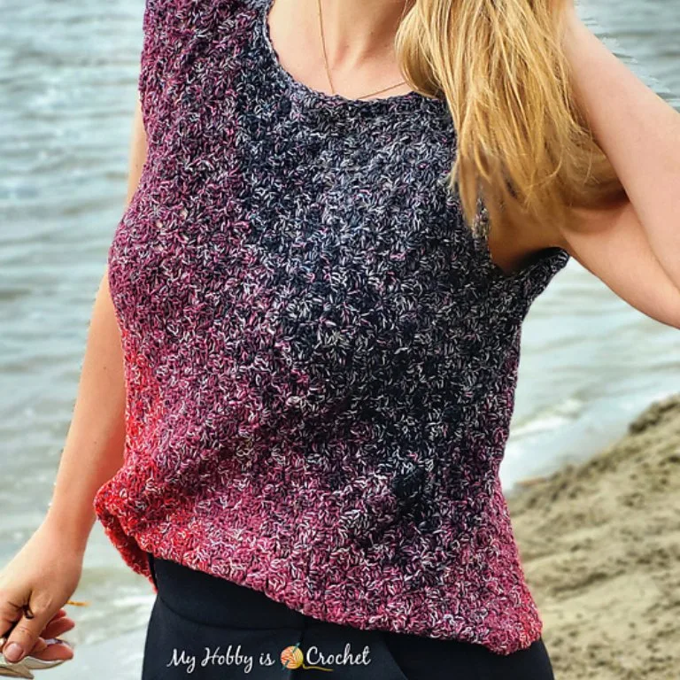 A person by the beach wearing a crochet lightweight sleeveless blouse, enjoying the coastal breeze.