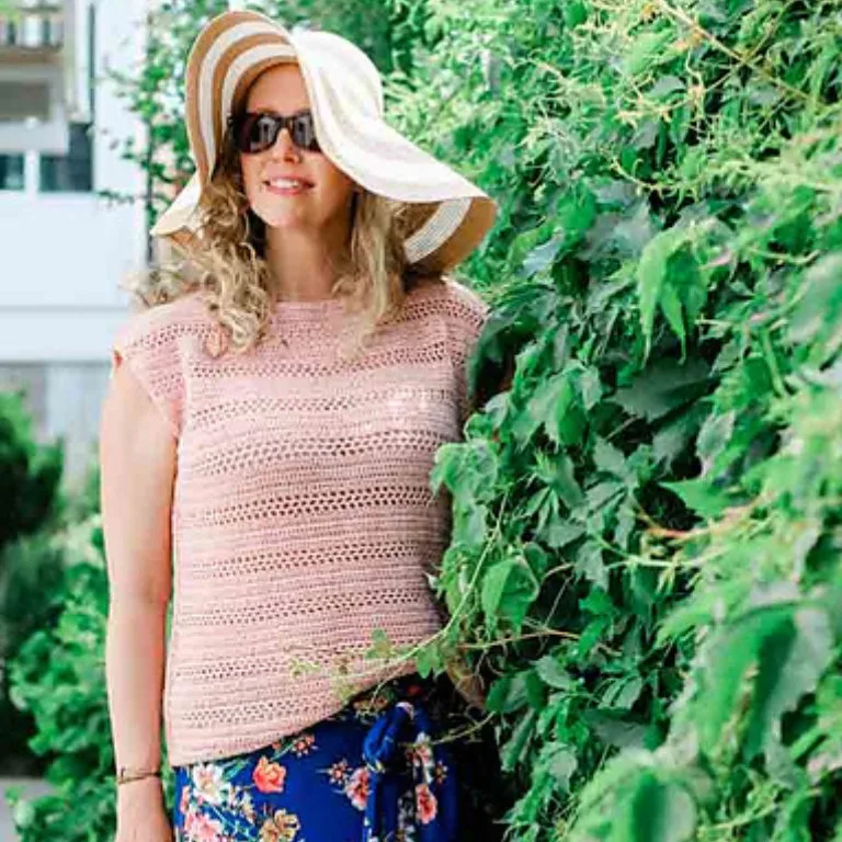 A woman wearing an elegant summer hat and a simple, relaxed-fit crochet top, enjoying a stylish and comfortable summer look.