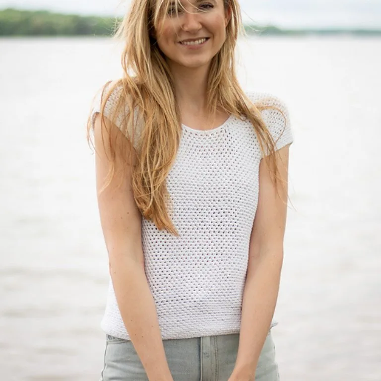 A woman wearing a simple crochet t-shirt on the beach, showcasing a classic and timeless tee design.