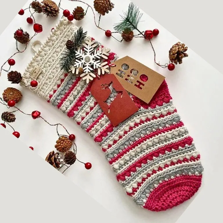 A large crochet stocking with tags, adorned with festive Christmas picks.