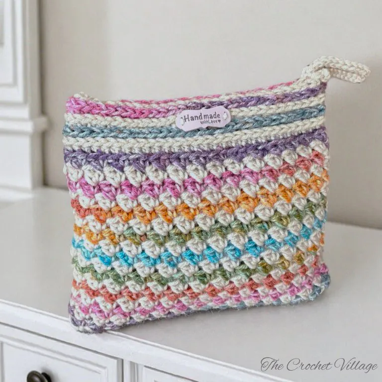 Handmade crochet wildflower makeup bag arranged on a bedroom dresser with cosmetics and accessories, styled for home decor
