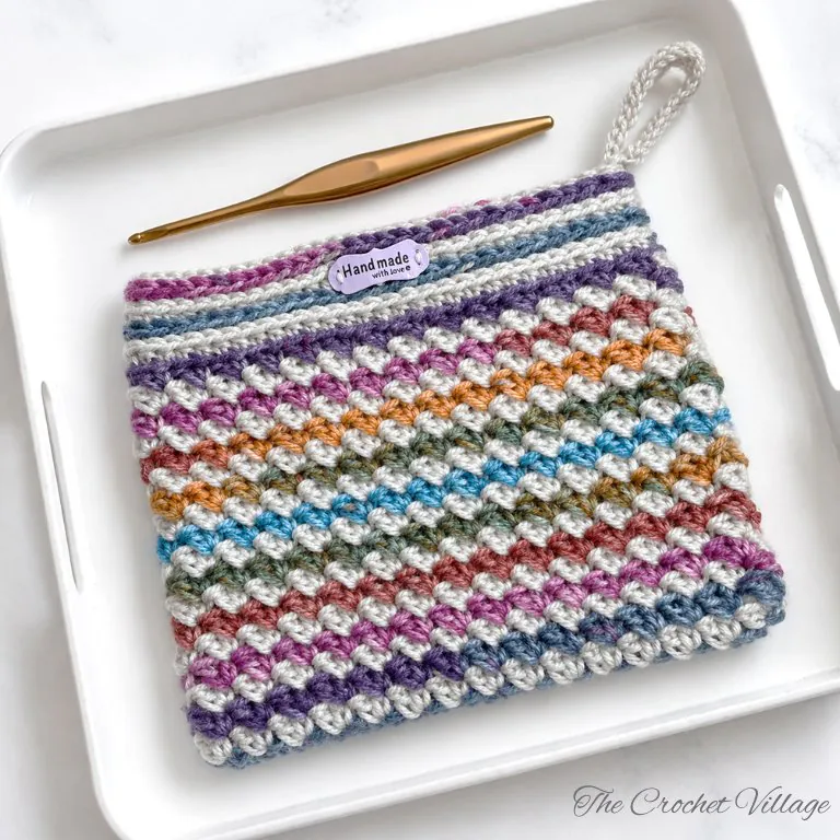 Flat lay overhead view of crochet wildflower makeup bag showing overall pattern design and finished dimensions