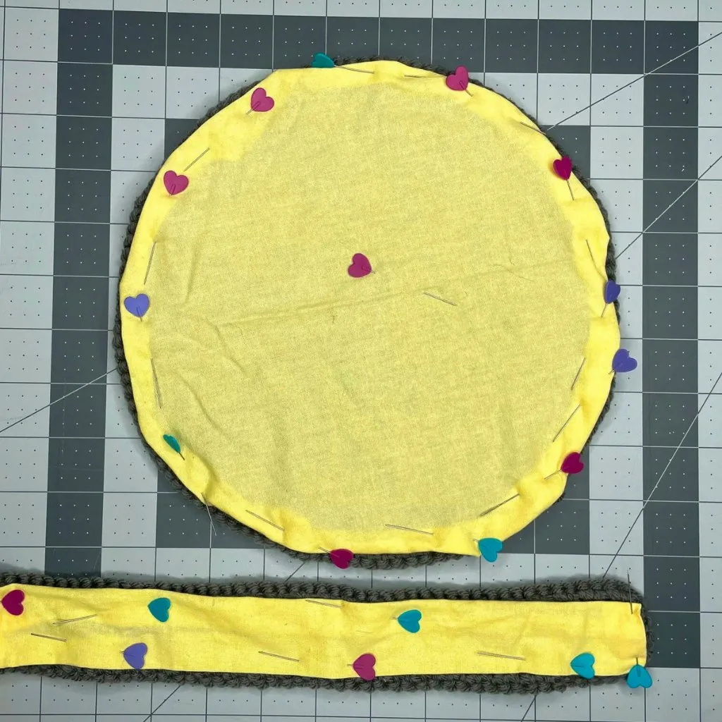 Fabric pinned to two crochet pieces—a round one and a rectangular one—demonstrating how to line a crochet circle bag.