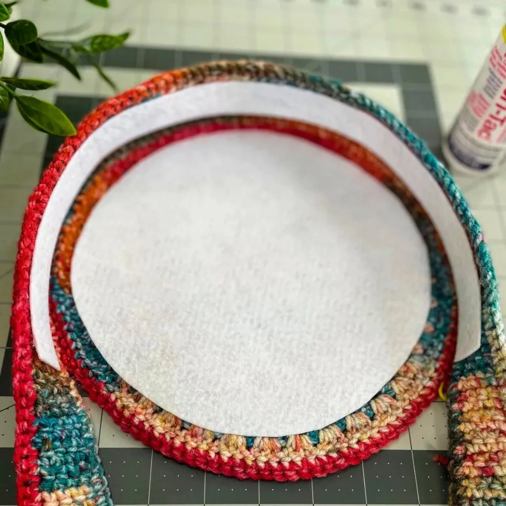 A close-up of adding fabric interfacing to the inside of a crochet bag, showing the reinforcement process.