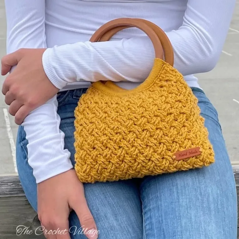 Woman holding a handmade crochet handbag with round wooden handles, showing the textured Celtic weave stitch detail