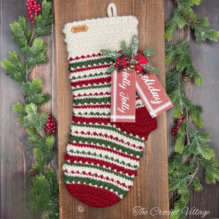 A large, textured, festive crochet Christmas stocking adorned with a Christmas tag and holiday decor.
