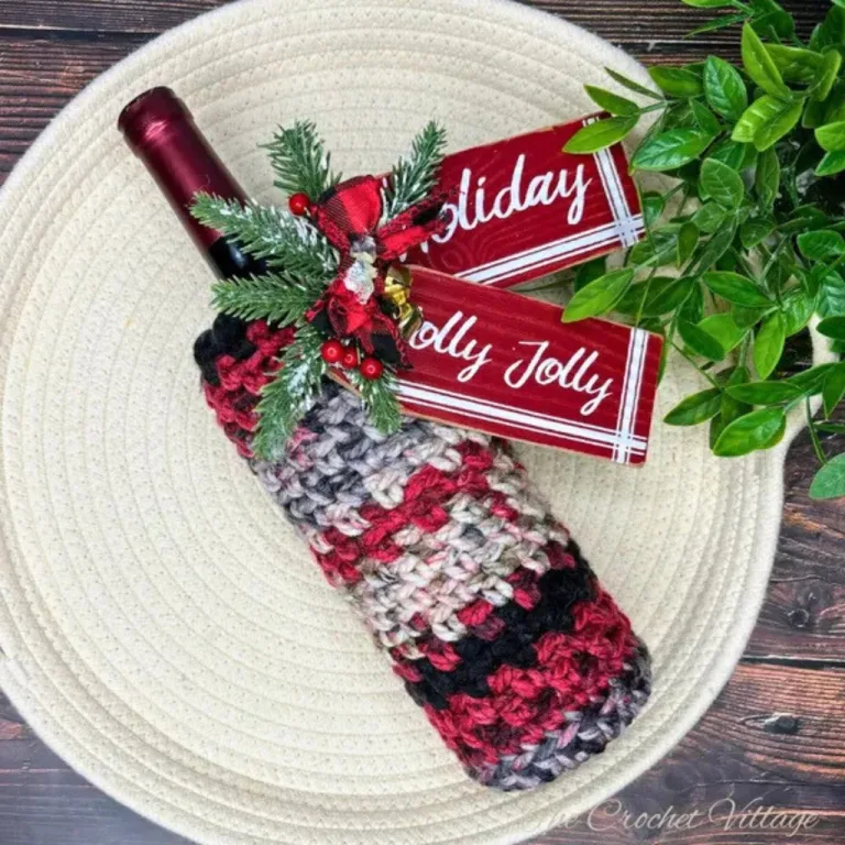 A wine bottle in a festive crochet bottle cover, decorated with a Christmas tag for the perfect holiday gift.
