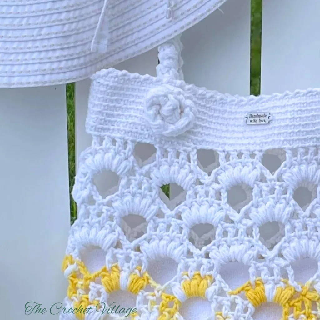 Alt text: Close-up of the top of a crochet bag, showcasing the beautiful, thick crochet handle with detailed stitching.