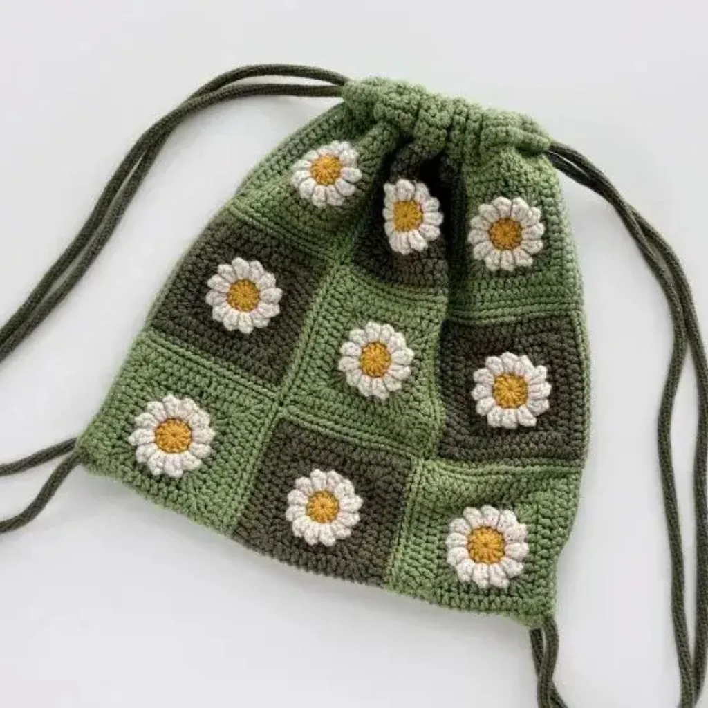 A crochet daisy granny square backpack with strings for closure.