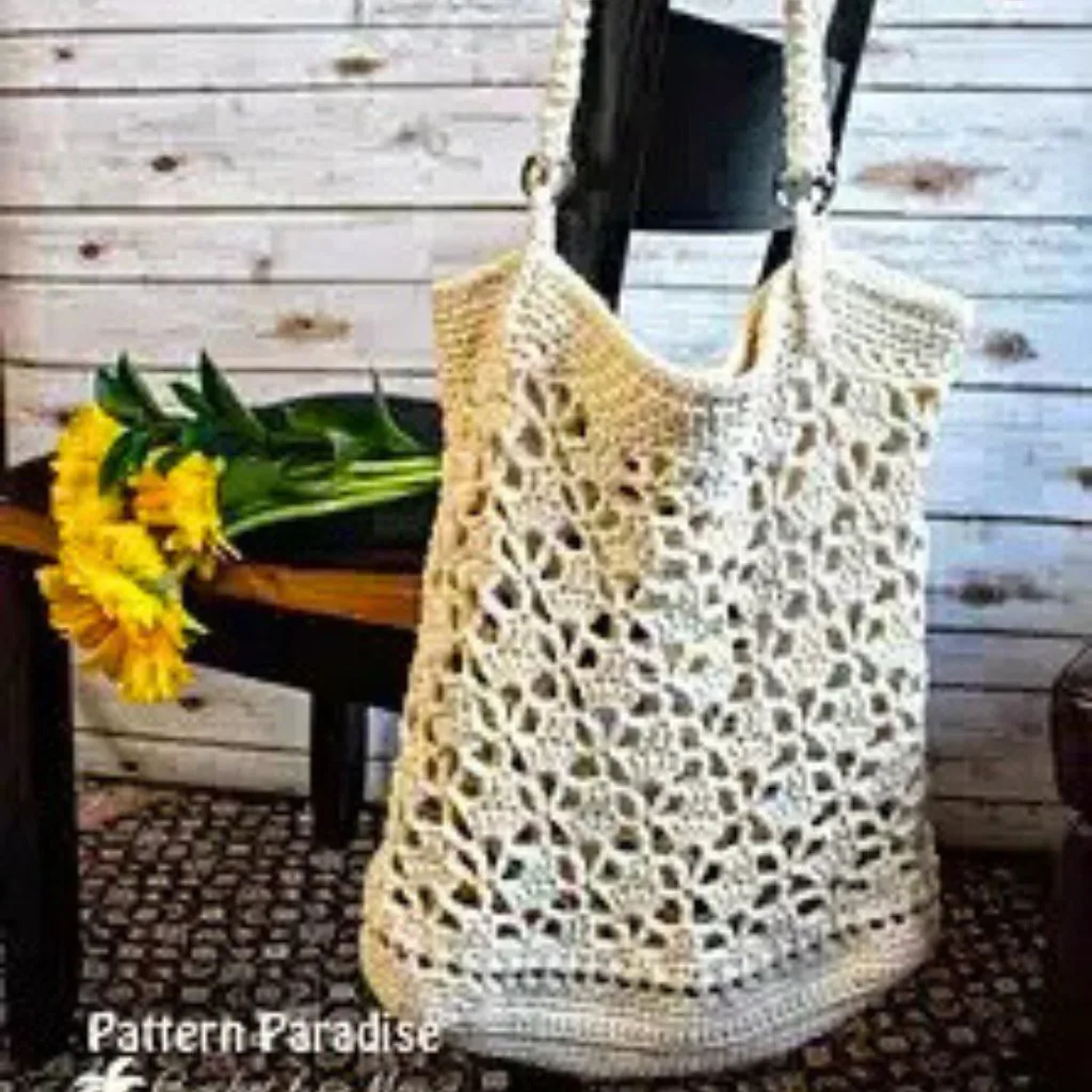 A crochet market bag hanging on a chair, with flowers placed beside it.