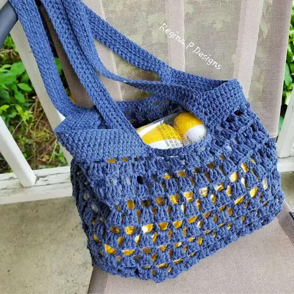 A crochet mesh market bag filled with yarn, resting on a chair.