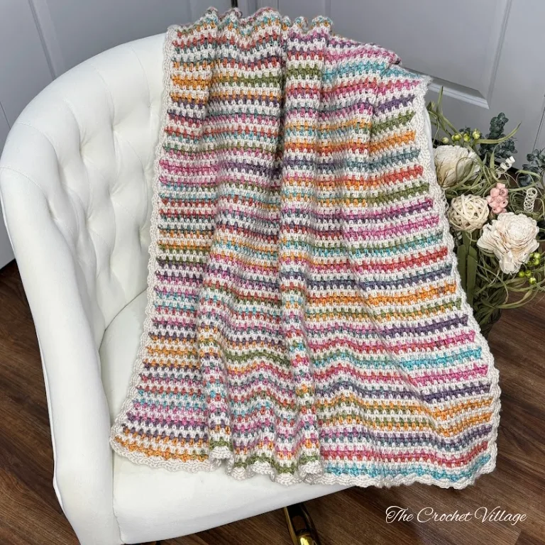 A striped moss stitch crochet throw blanket draped over a chair.