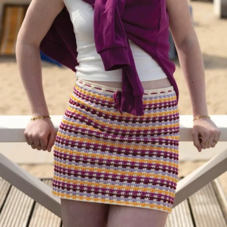 A person wearing a lightweight crochet striped mini skirt, perfect for warm weather, with a stylish and playful handmade look.