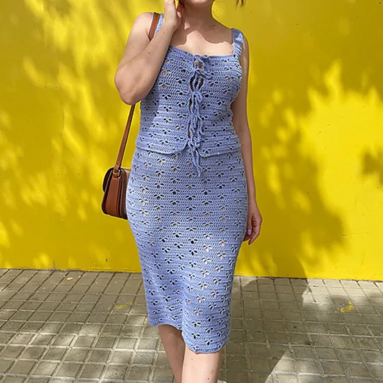 A woman wearing a charming two-piece crochet top and skirt set, showcasing intricate handmade details and a stylish, coordinated look.