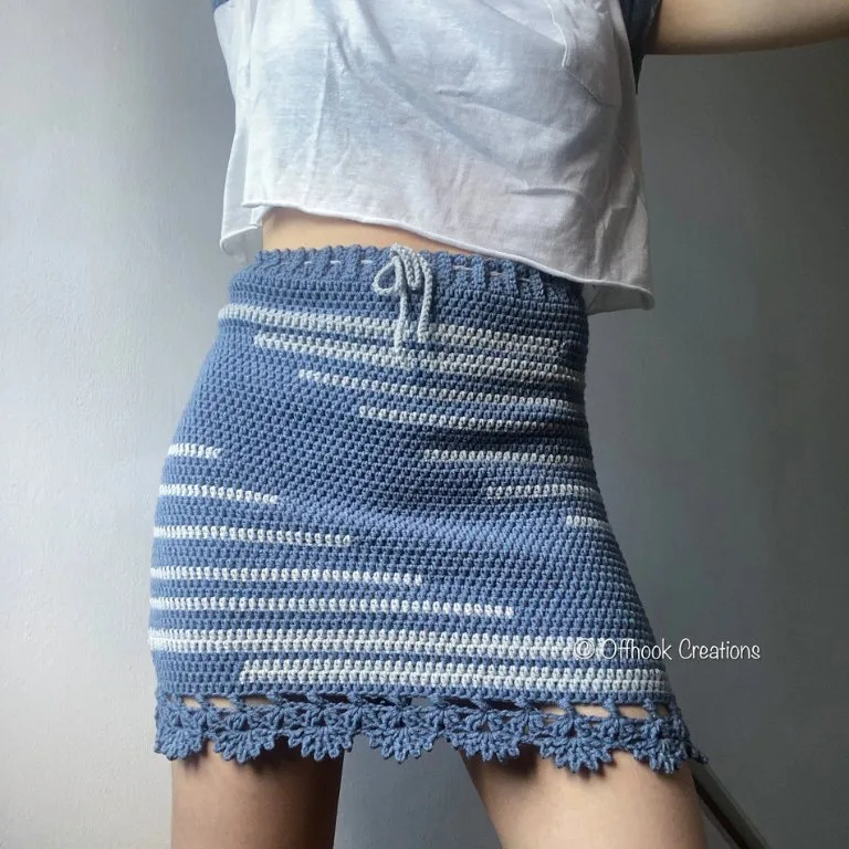 A woman modeling a simple fitted crochet skirt with a delicate lacy border, showcasing a stylish and elegant design