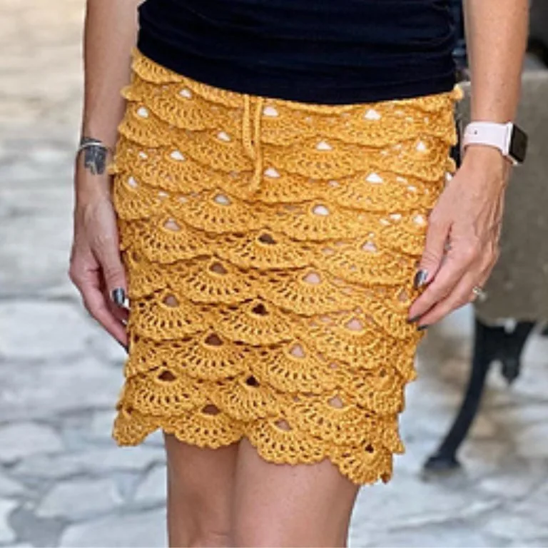 A woman wearing an elegant midi crochet skirt with a gorgeous ruffled, lacy shell-like stitch