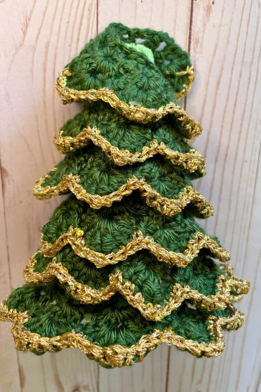 A photo showing how to wrap the fabric around the foam cone to form a small 3d crochet christmas tree
