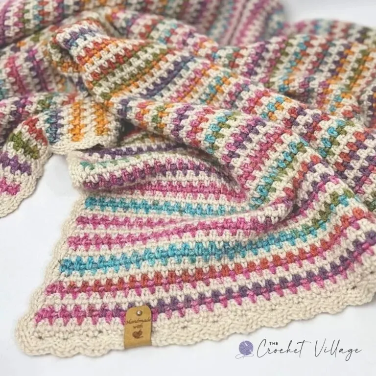 Close up of crochet moss stitch texture in cream and variegated yarn on a folded blanket