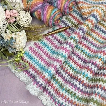 Crochet moss stitch blanket in rainbow variegated and cream yarn with a gorgeous border